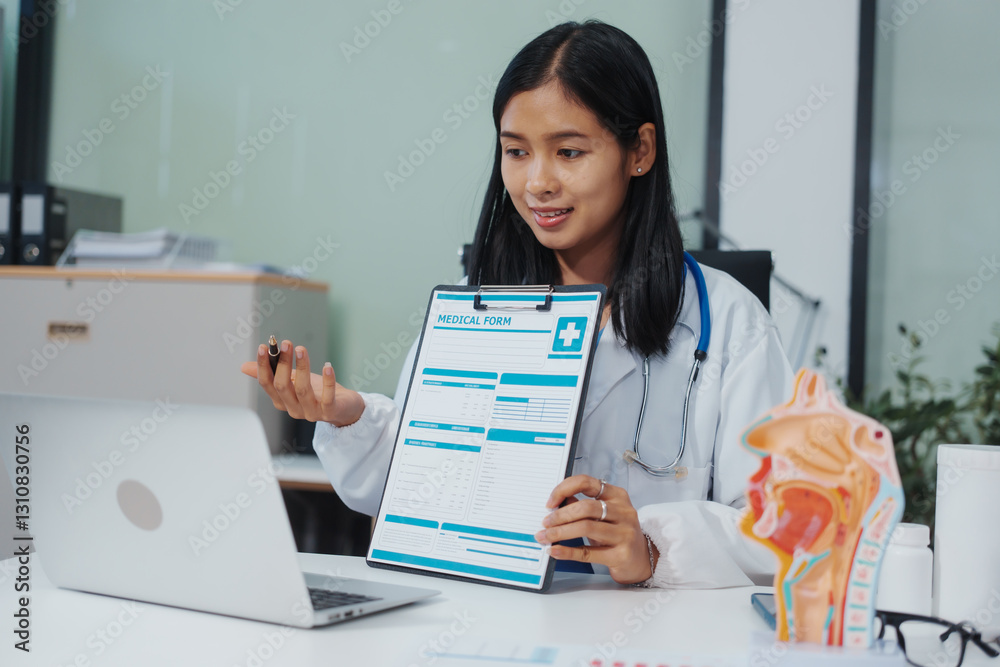 An Asian female doctor uses a respiratory system model while working on a computer, planning treatment,consulting online, explaining respiratory care to patients via a medical video call in a clinic An Asian female doctor uses a respiratory system model while working on a computer, planning treatment,consulting online, explaining respiratory care to patients via a medical video call in a clinic