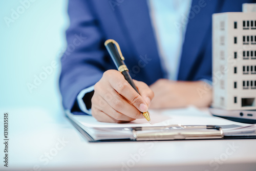 A female employee works at her desk in a real estate office, managing condo sales in the city. She communicates with clients, handles listings, and provides information about available properties