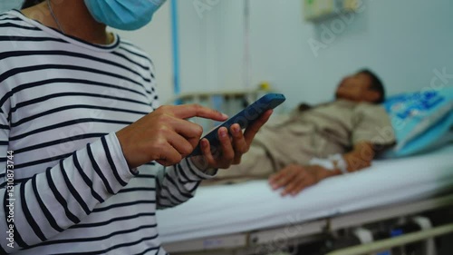 A daughter sits by her elderly father's hospital bedside, caring for him, giving him medicine, holding his hand and encouraging him as he struggles with the stress of his treatment and medical bills