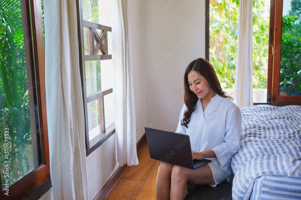 Portrait of a woman using and working on laptop computer in bedroom Portrait of a woman using and working on laptop computer in bedroom