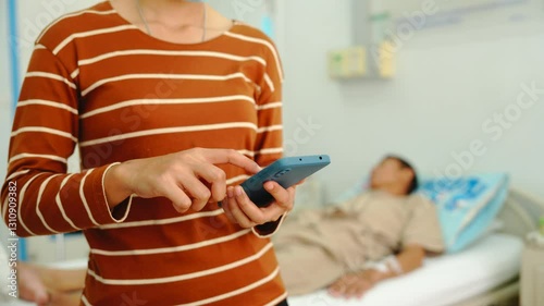 A daughter sits by her elderly father's hospital bedside, caring for him, giving him medicine, holding his hand and encouraging him as he struggles with the stress of his treatment and medical bills