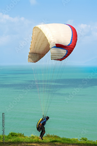 An unidentified man is getting ready for paragliding near the sea.