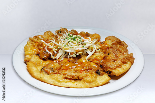 Crispy fried mussels with a spicy dipping sauce served on a white ceramic plate is a delicious Thai street food. and gained popularity.