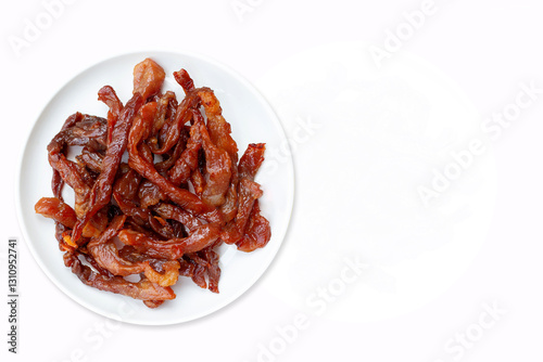 Fried dried pork on a white round plate on a white background. Top view.