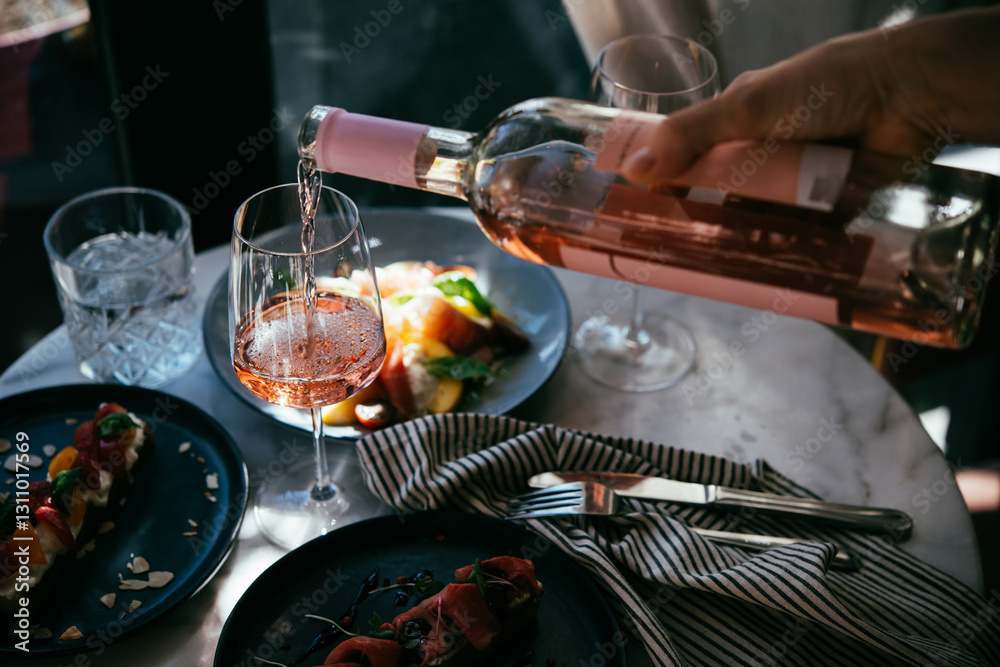 Pouring rose wine at a dinner party with friends in a bar or restaurant.