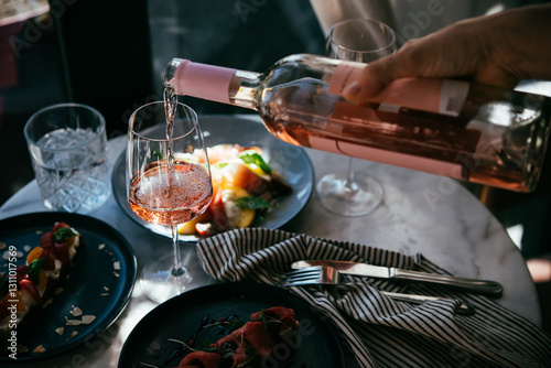Obraz na płótnie Pouring rose wine at a dinner party with friends in a bar or restaurant. w salonie