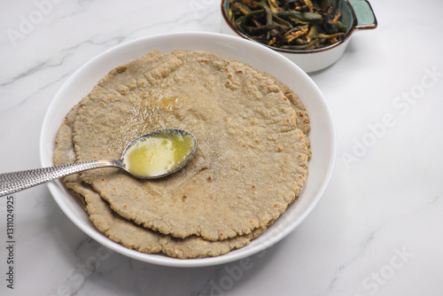 Jowar flour flatbread known as bhakar or jawari bhakri. served with ghee, spicy garlic or lasun chutney, bhindi or lady finger sabji. farmer's food. Maharashtrian village food. copy space. photo