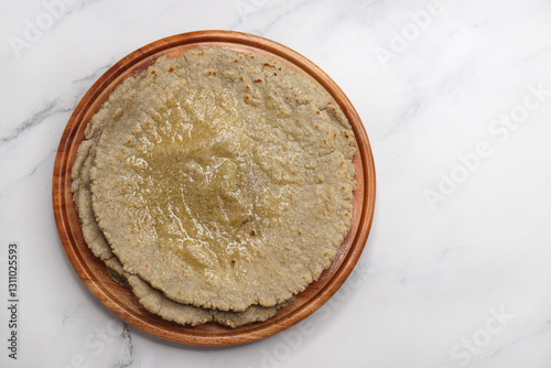 Jowar flour flatbread known as bhakar or jawari bhakri. served with ghee, spicy garlic or lasun chutney, bhindi or lady finger sabji. farmer's food. Maharashtrian village food. copy space. photo
