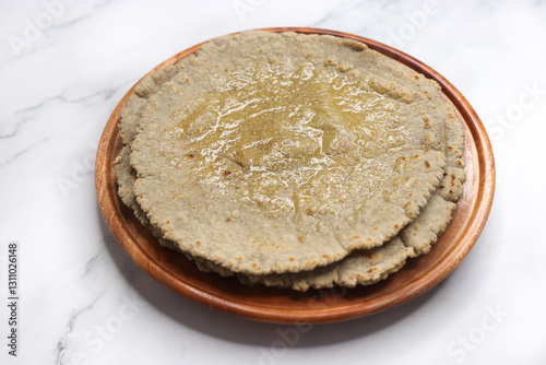 Jowar flour flatbread known as bhakar or jawari bhakri. served with ghee, spicy garlic or lasun chutney, bhindi or lady finger sabji. farmer's food. Maharashtrian village food. copy space. photo
