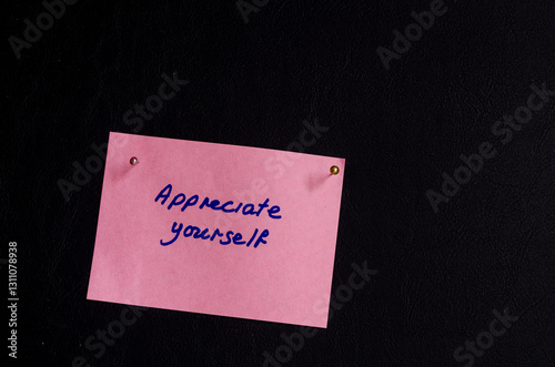 Post-it note saying ' Appreciate yourself' on pink note with black background encouraging mental health awareness photo