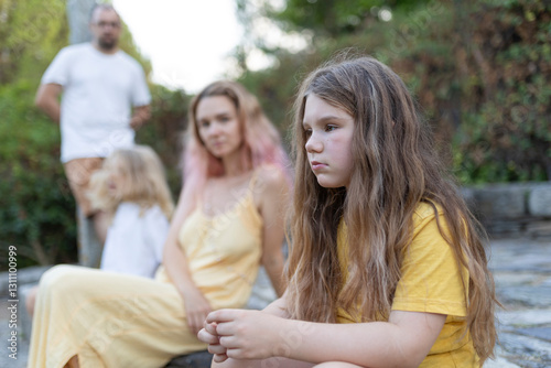 Sad girl feeling excluded from family gathering outdoors