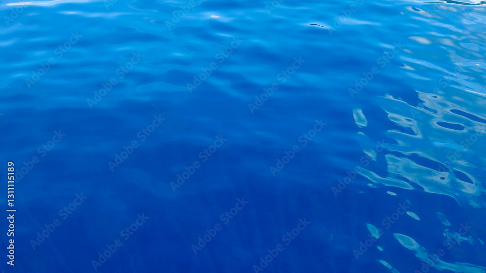 Obraz premium Blue water background. Top view of flat water surface. Aerial view of calm sea surface with clear transparent blue water.