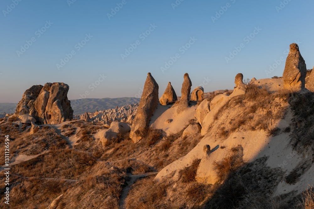 Obraz premium View of Cappadocia's unique rock formations under a clear blue sky during sunset