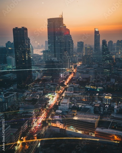 Εκτύπωση καμβά View of a bustling cityscape at sunset with skyscrapers and vibrant street light