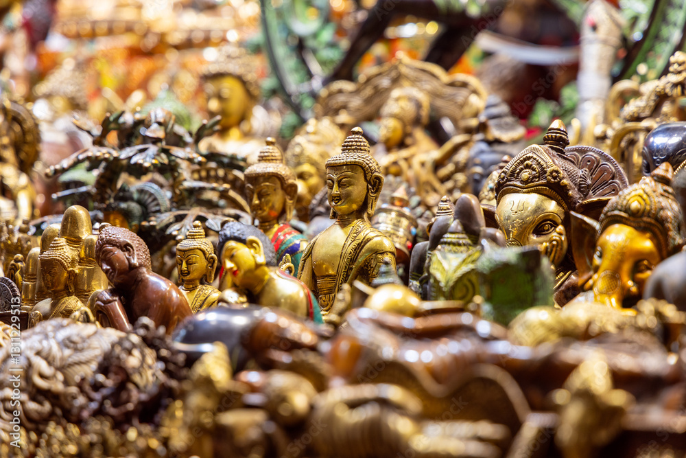 Hindu and Buddhist deity statues made of metal with gold and bronze finishes closely arranged in a market with a central focus on a Buddha figure in the foreground Hindu and Buddhist deity statues made of metal with gold and bronze finishes closely arranged in a market with a central focus on a Buddha figure in the foreground