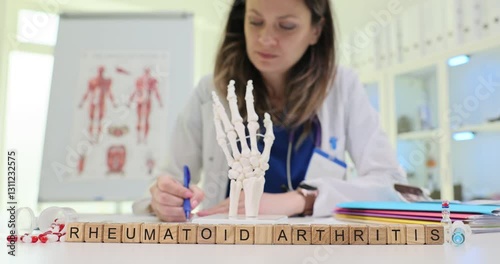 A healthcare professional examines a detailed model of a human hand to discuss the complexities of rheumatoid arthritis