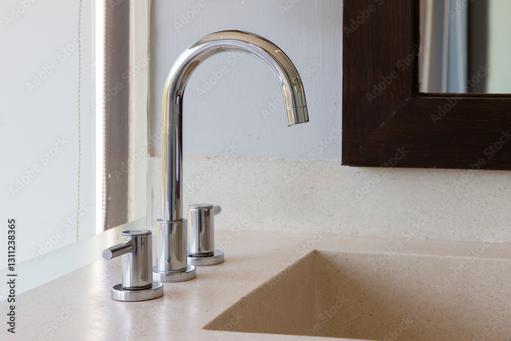 A bathroom sink with a chrome faucet and a mirror above it A bathroom sink with a chrome faucet and a mirror above it