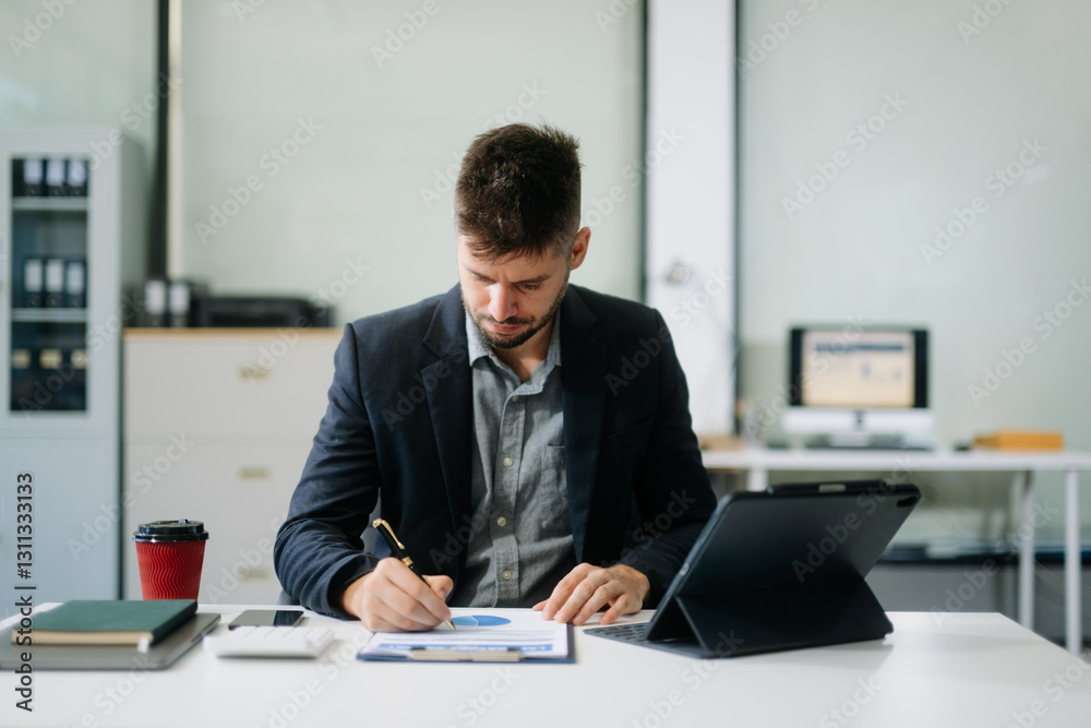 Confident businessman working on finance analysis with a tablet and laptop at office desk. professional workplace concepts.. Confident businessman working on finance analysis with a tablet and laptop at office desk. professional workplace concepts..