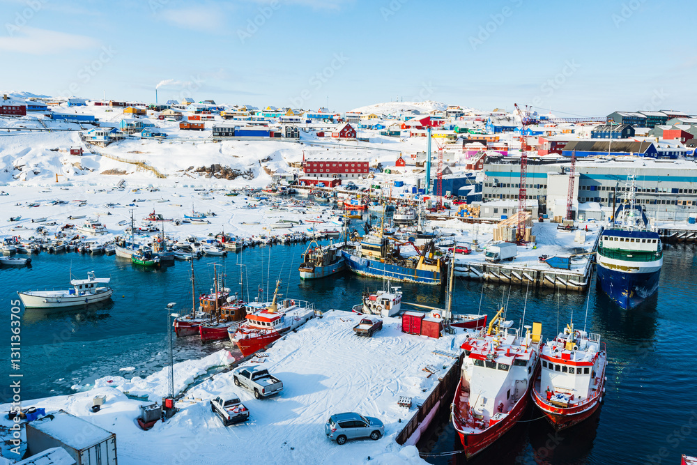 Obraz premium Boat activity in the icy Port of Ilulissat showcasing the vibrant town and colorful buildings under a clear sky