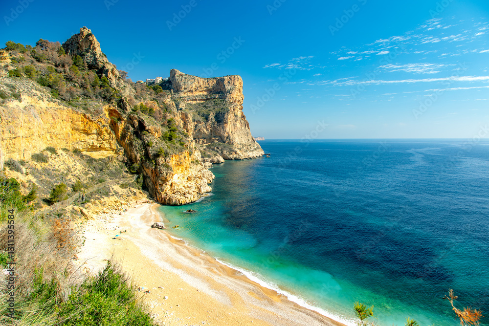 Obraz premium Turquoise waters and golden cliffs at Costa Blanca’s hidden beach, Moraig