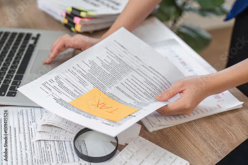 Tableau sur toile Businesswoman holding tax documents and navigating her laptop in an office setting