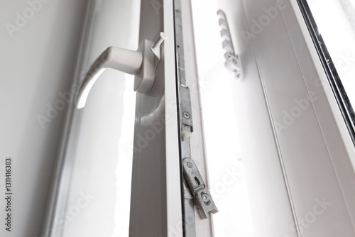 Close-up of a double-glazed balcony frame with a latch and fastening for safe ventilation. Single-sided window handle
