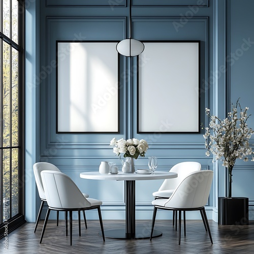 Two large, thick black frames hang on the wall of an elegant dining room. The room features modern white chairs, a white round table, and soft pastel blue walls. The lighting is soft, and a flower bou