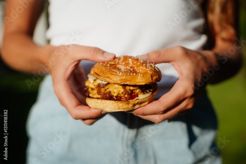 Smashed cheeseburger with sesame bun outdoors in summer