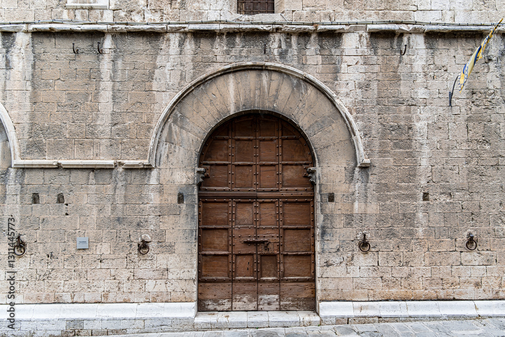 A brown door with a white arch above it in Gubbio Italy Umbria A brown door with a white arch above it in Gubbio Italy Umbria