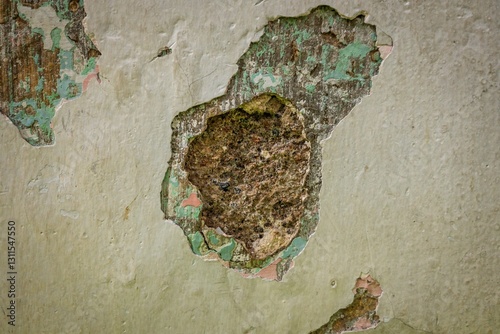 Fototapeta Naklejka Na Ścianę i Meble -  Close-up of a deteriorating wall with peeling paint, revealing multiple layers of old paint and exposed rough plaster, showcasing decay, texture, and aging.