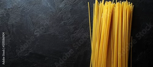 Panel kuchenny z motywem Yellow spaghetti strands arranged neatly on the left against a black textured background with ample copy space on the right side of the image