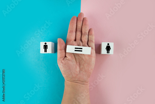 Gender equality symbol. Hand turns cube and changes inequality sign to equal sign between male and female symbols. Nice pink and blue background