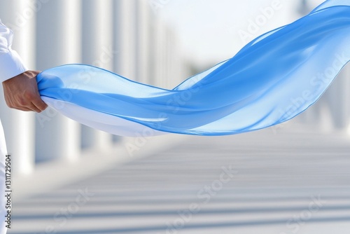 A person gracefully holding a flowing blue fabric in a bright setting
