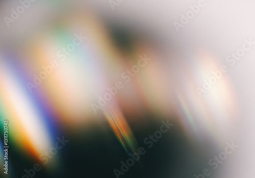 Soft focus abstract diagonal streaks of rainbow prismatic light and colour leaks on blurred dark and grey backdrop