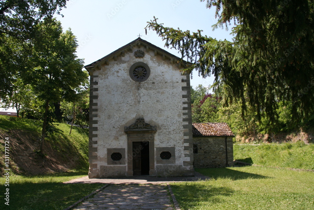 The exterior facade of Oratorio della Madonna della Neve in Reggio Emilia, Italy, a small church with a simple yet historic design. Trees and greenery surround the building. The exterior facade of Oratorio della Madonna della Neve in Reggio Emilia, Italy, a small church with a simple yet historic design. Trees and greenery surround the building.
