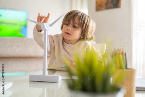 Preschooler interacts with a miniature wind turbine model at home, exploring renewable energy concepts and engaging in stem learning, fostering environmental awareness and sustainability education