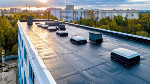 Urban concrete building rooftop with rolled waterproofing and skylights at sunset