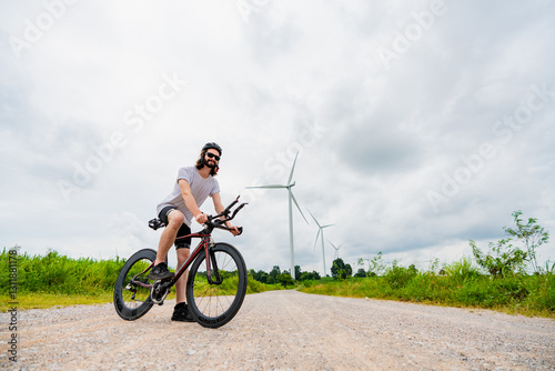 Cyclist enjoys a scenic ride along a gravel path with wind turbines in the background on a cloudy day