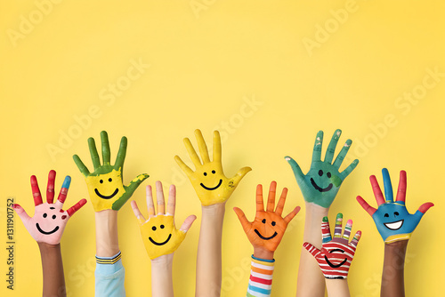 A Lot of painted hands raised up. Group of multiracial funny children funny kids hands up on the yellow background. Copy space.