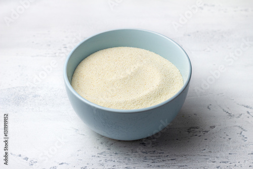 Light blue ceramic bowl filled with semolina sits on a textured light grey marble surface