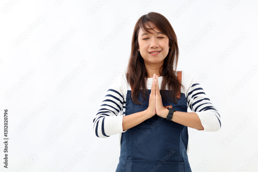 Asian young woman wearing apron over white background praying with hands together asking for forgiveness smiling confident eyes closed. Asian young woman wearing apron over white background praying with hands together asking for forgiveness smiling confident eyes closed.