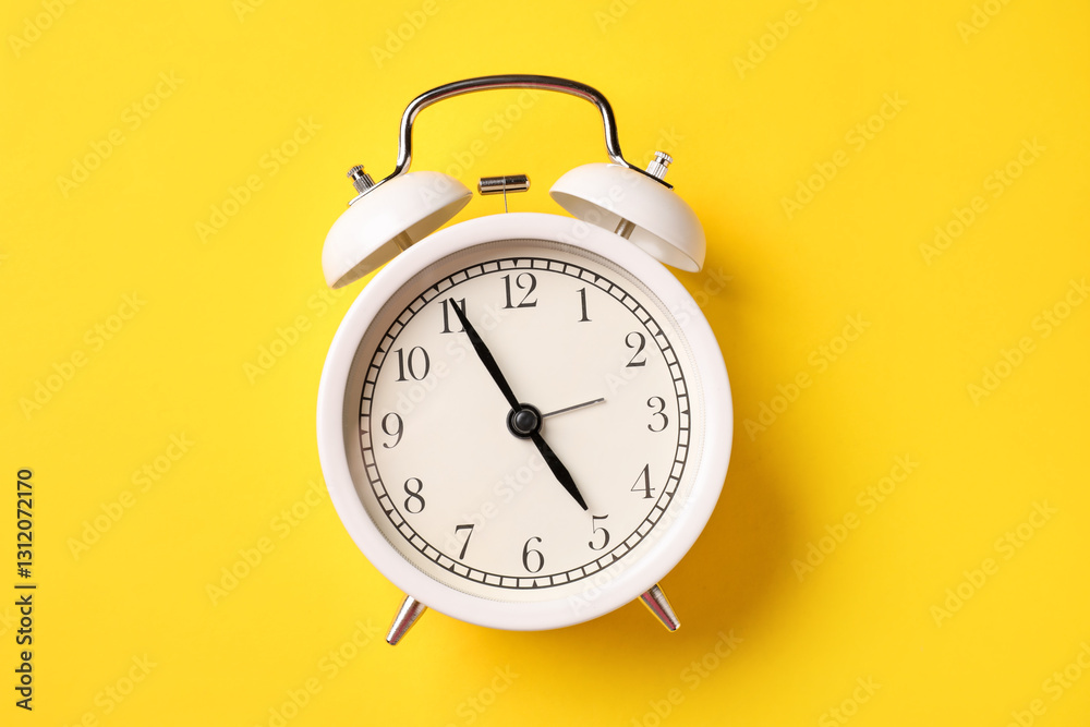 White alarm clock on yellow background, top view White alarm clock on yellow background, top view