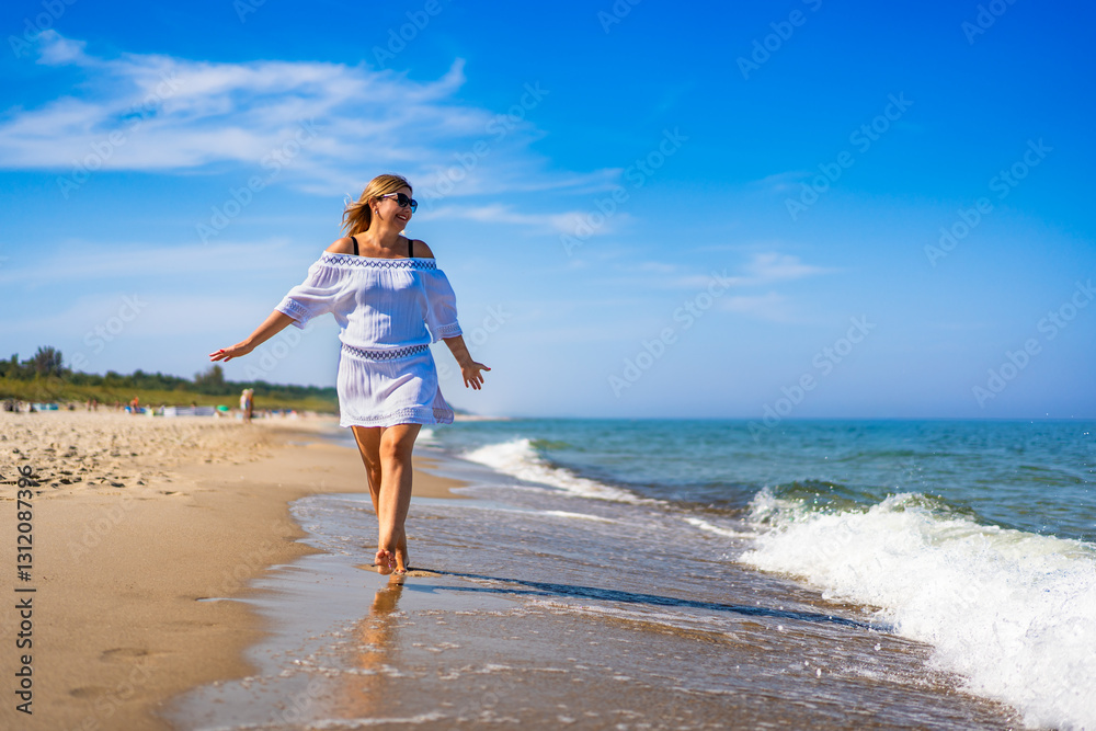 Summertime by sea. Beautiful middle aged woman tourist walking on sandy beach on sunny summer day. Front view Summertime by sea. Beautiful middle aged woman tourist walking on sandy beach on sunny summer day. Front view