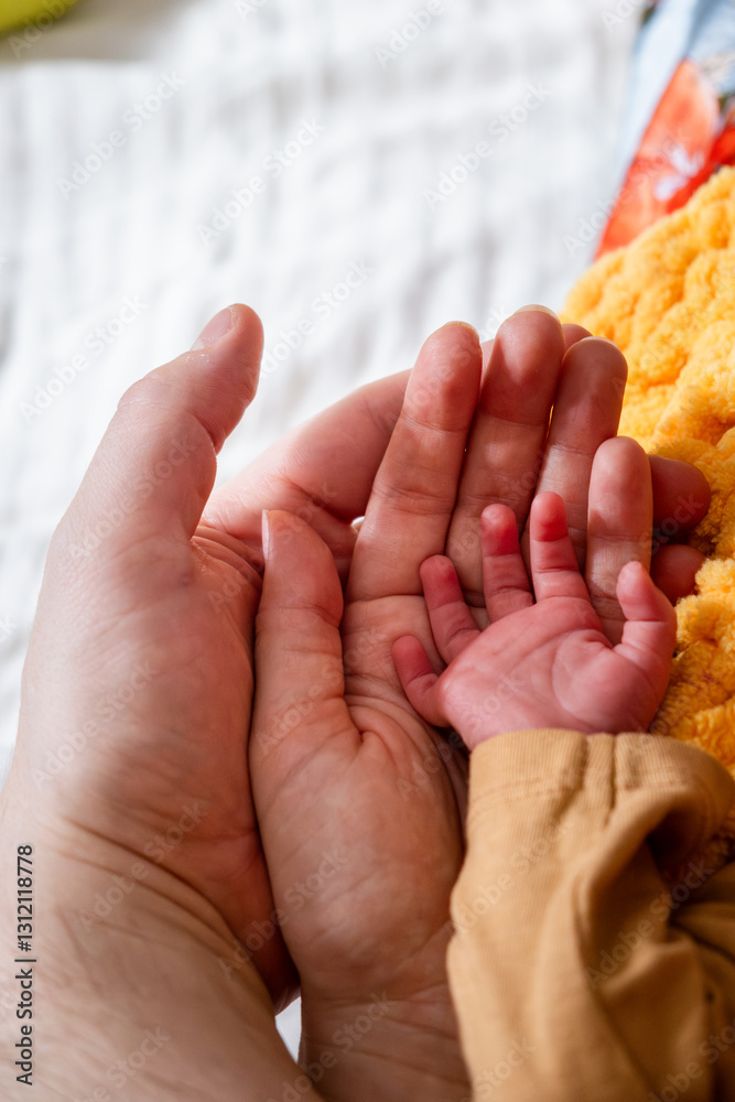 Adult and Baby Hand on Yellow Knitted Blanket