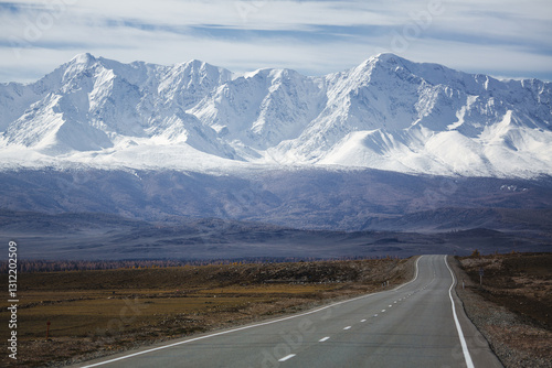 Obraz na płótnie A road stretching into the distance toward the majestic North Chuysky Ridge with snow-capped peaks in the Altai Republic, creating a breathtaking and serene scene. w salonie