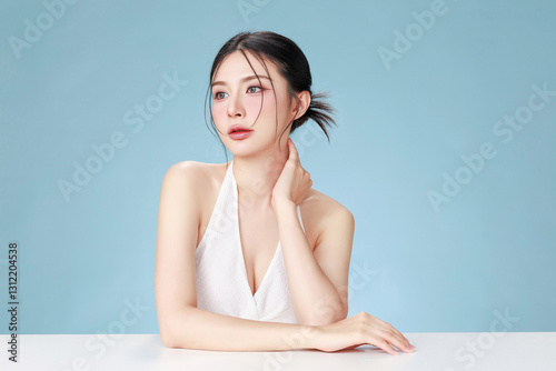Beautiful young Asian woman model bun hair with natural makeup on face clean fresh skin on isolated blue background. Cute girl portrait, Facial treatment, Body care, Beauty and Spa.