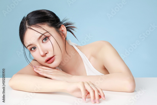 Beautiful young Asian woman model bun hair with natural makeup on face clean fresh skin on isolated blue background. Cute girl portrait, Facial treatment, Body care, Beauty and Spa.