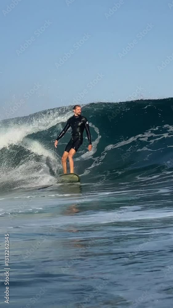 Surfer ridding a blue wave and making a spray in Indian Ocean.Surfing action shot. Wide angle view.Vertical video Surfer ridding a blue wave and making a spray in Indian Ocean.Surfing action shot. Wide angle view.Vertical video
