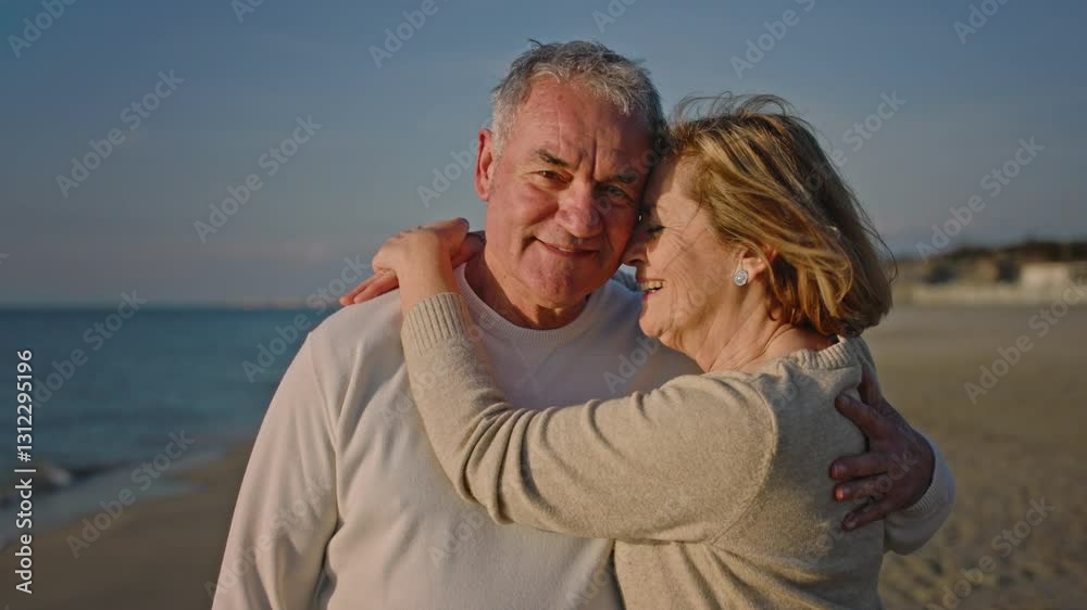 Portrait of couple of mature and old people enjoying summer at the beach looking to the camera taking a selfie together with the sunset at the background. Two active seniors traveling outdoors.