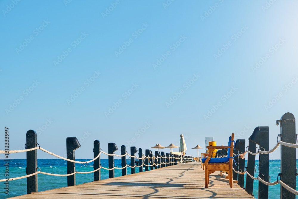 Fototapeta premium Wooden pier on sea stretching into distance beyond horizon on sunny summer day. Vacation and Travel Concept.